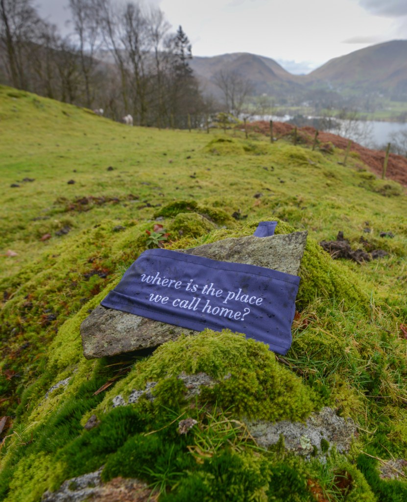 A stone wrapped in blue cloth with the words 'where is the place we call home?'