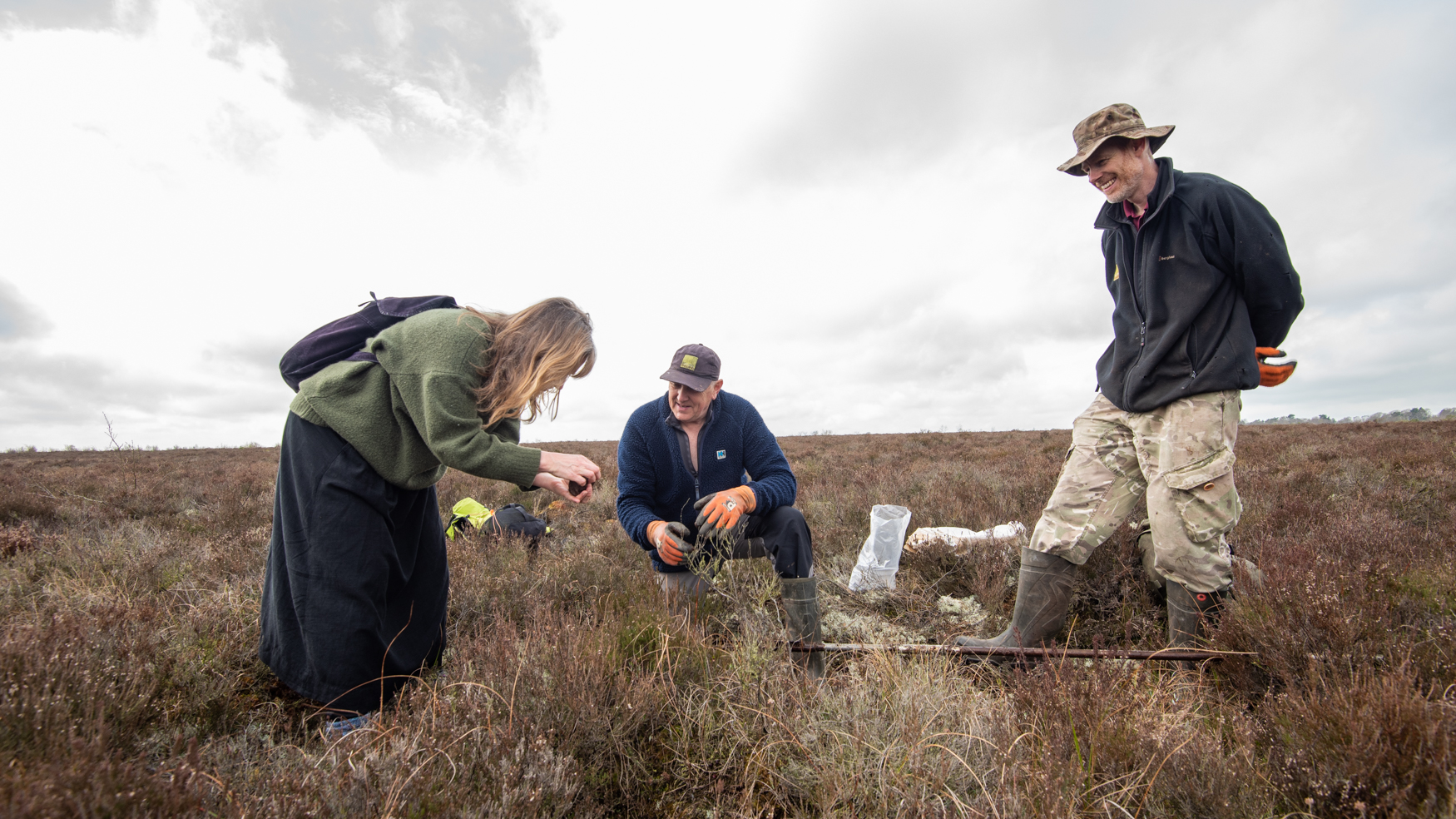 A woman and two men are looking at a peat sample taken from 9 metres beneath the surface of a raised mire.