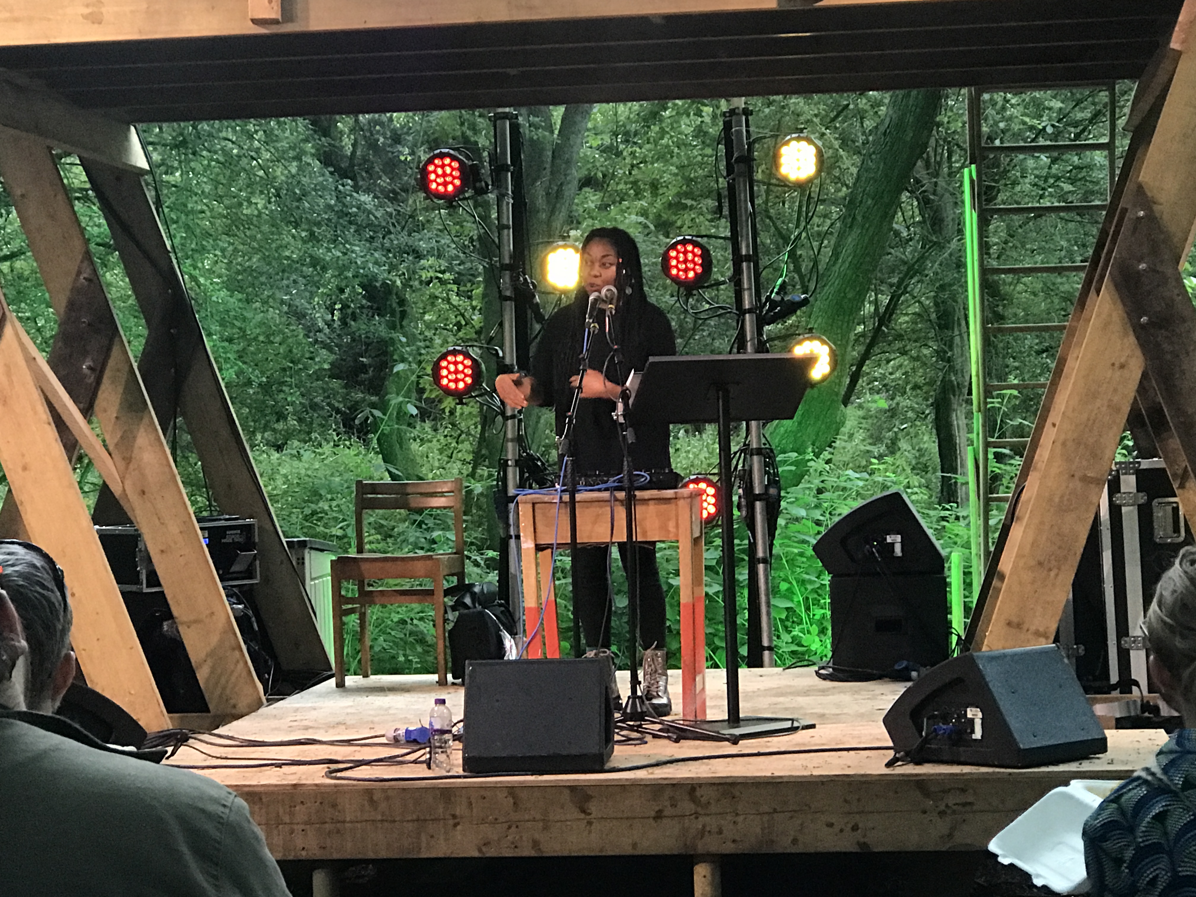 SheBeKeke stands on a stage giving a performance of spoken word and music