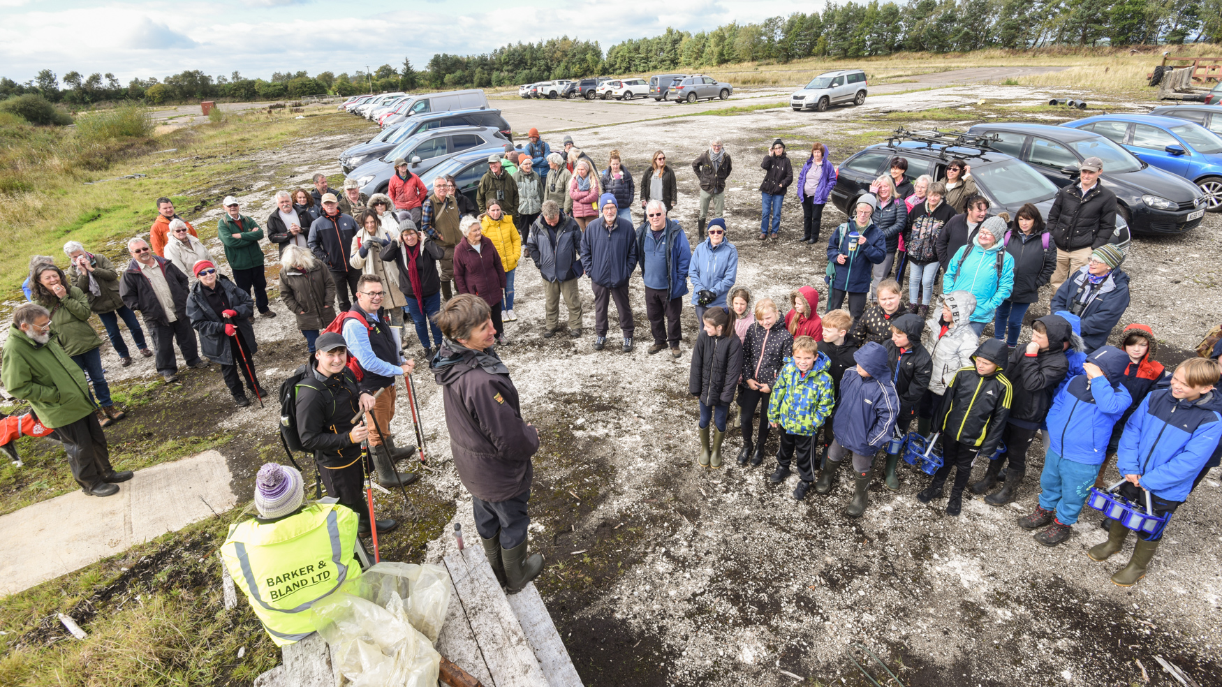 A group of people gathered in a car park before heading out on a walk