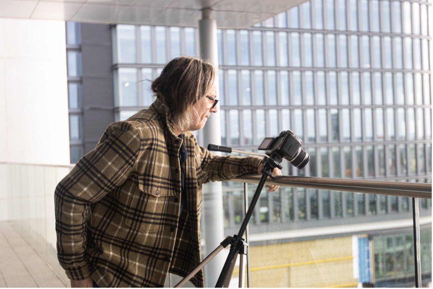 A man with a camera looks over a balcony