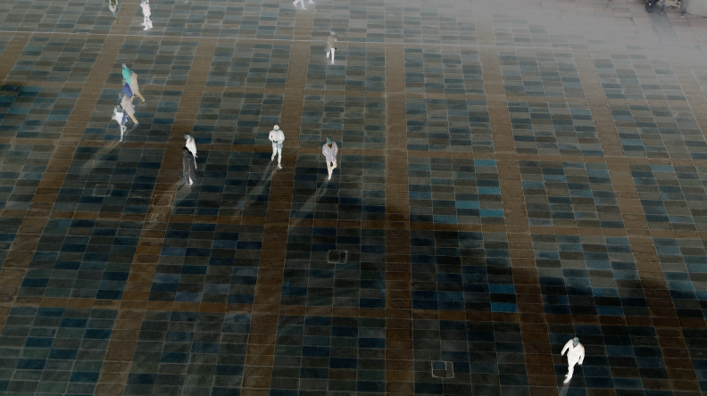 A still image from a video showing people walking across a tiled space