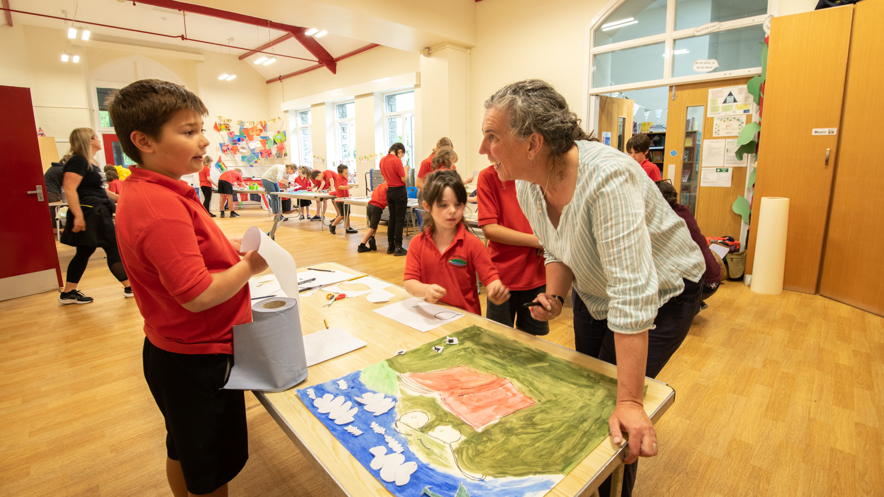 Children are making a painted collage, talking to an adult