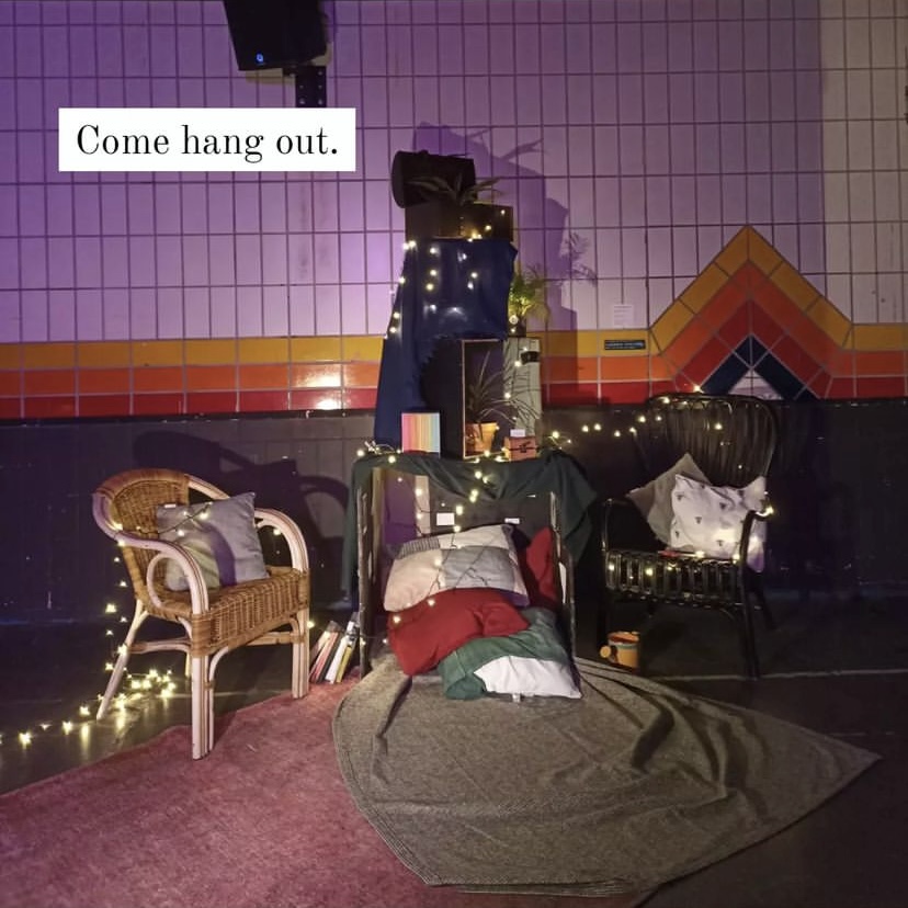 A stage set of two chairs, cushions, and a blanket