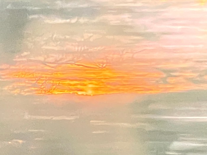 An abstract image suggesting sunset and clouds beyond winter trees