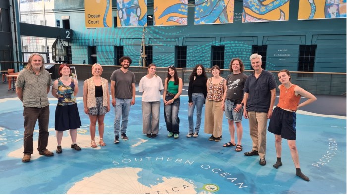 A group of people standing on a floor map of the ocean